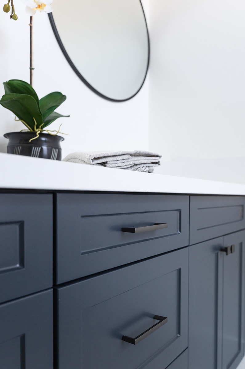 Close-up of a navy blue vanity against a white bathroom wall.