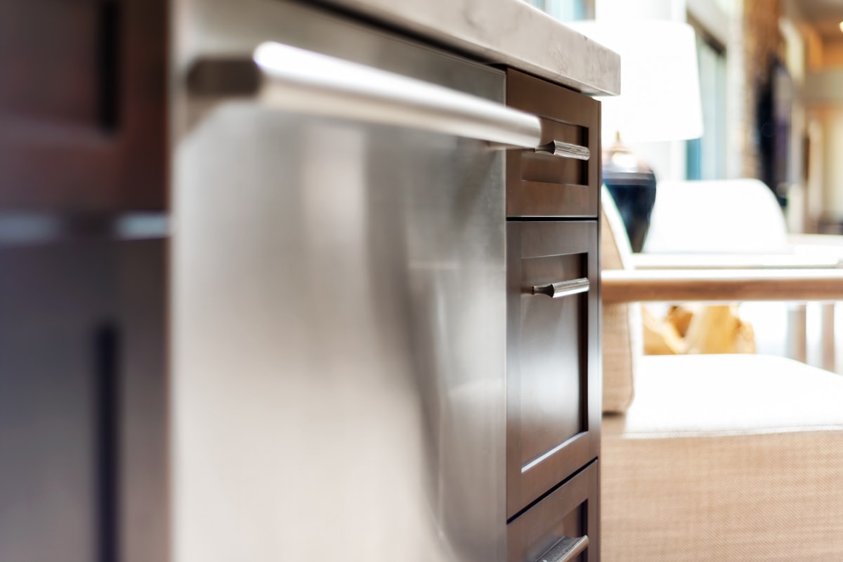 Close up of dark brown kitchen cabinets and dishwasher.