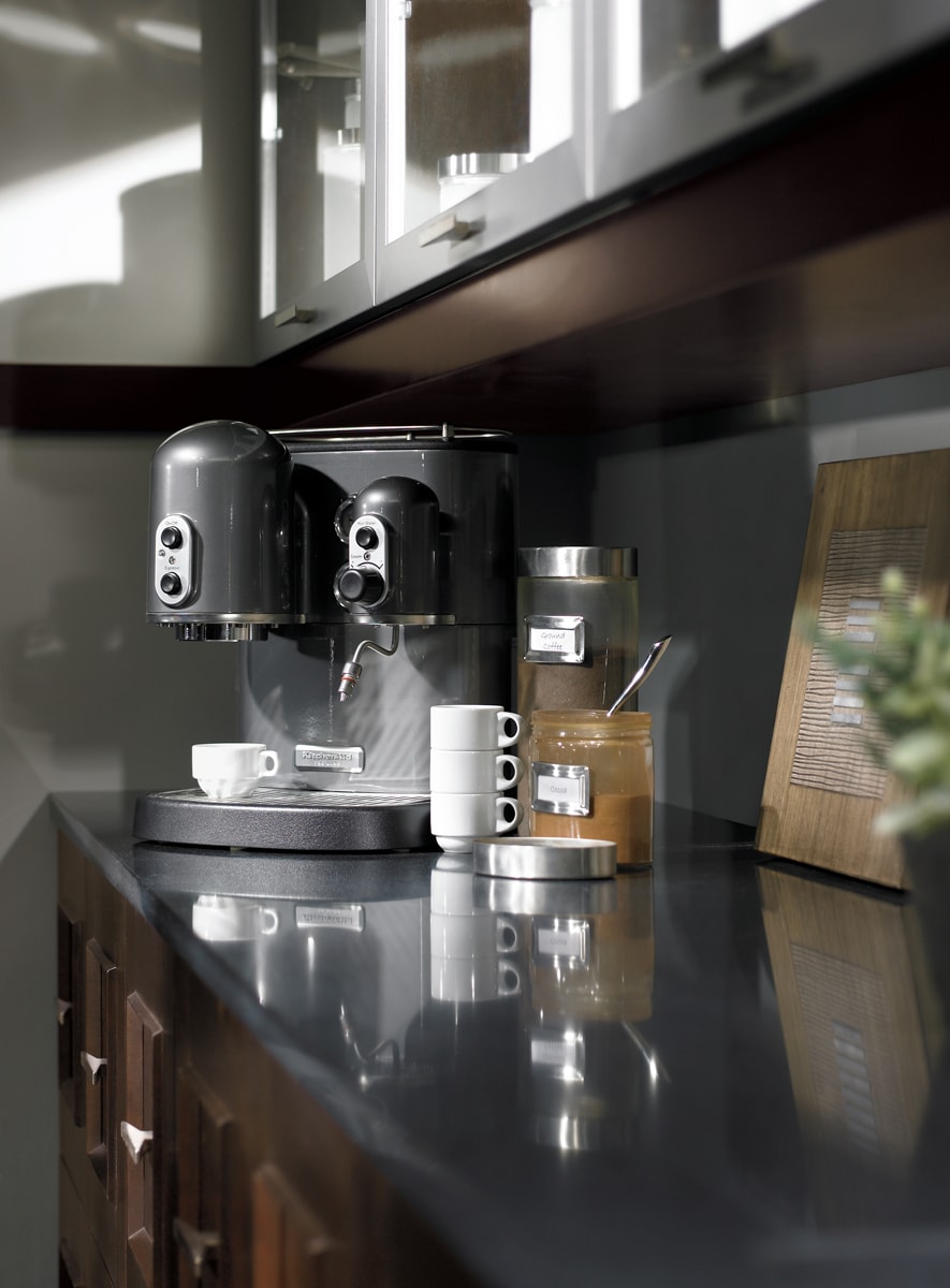 Coffee nook with warm brown cabinets and a shiny grey countertop.