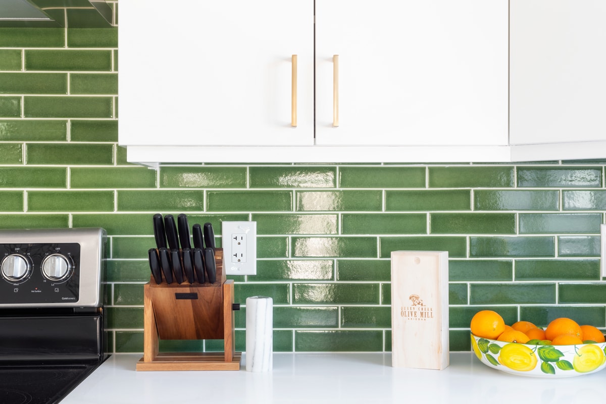 Green subway tile backsplash with a white countertop.