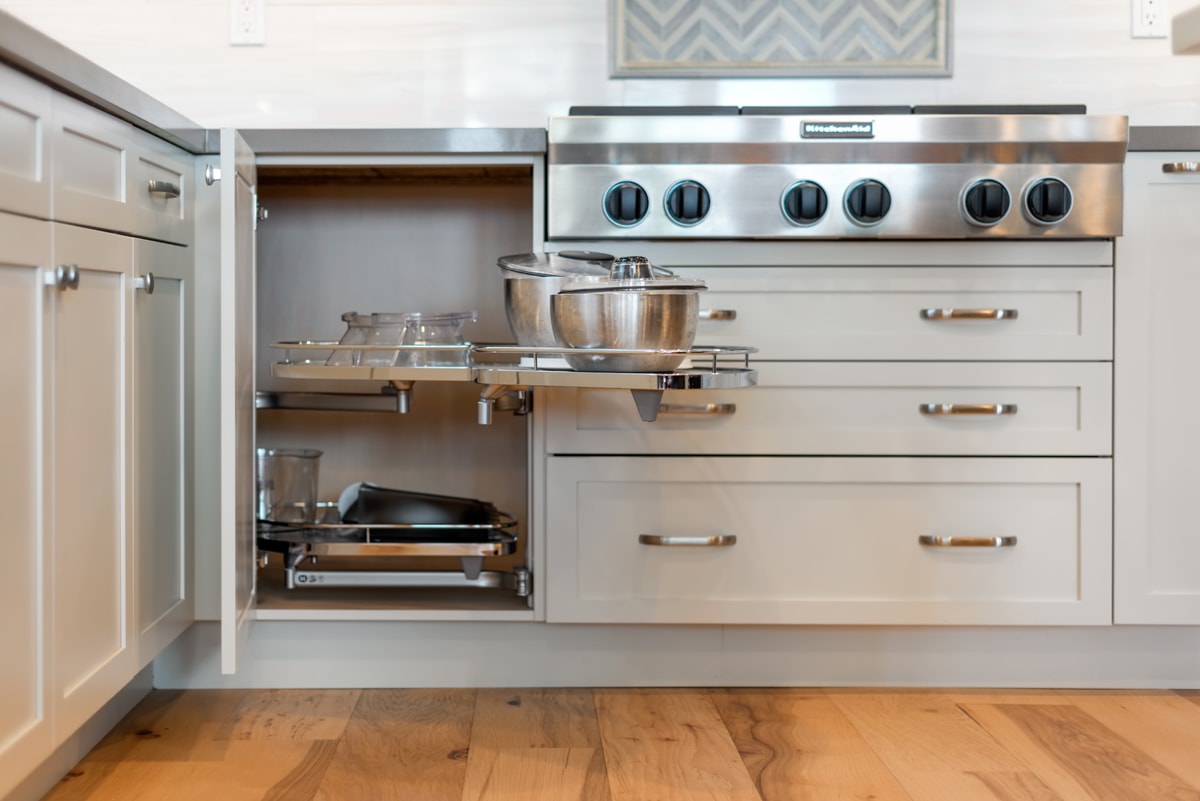 A white open corner cabinet with pull-out shelves.